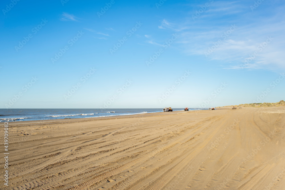 sand on a beach with boats in the distance preparing to enter the sea to fish