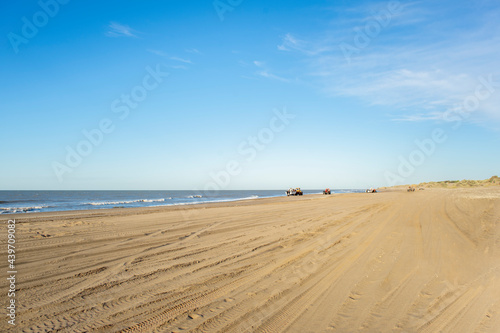 sand on a beach with boats in the distance preparing to enter the sea to fish