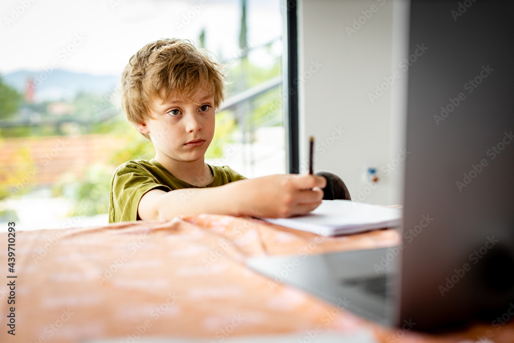 Bored young kid writing while Home Schooling during Covid Pandemic Bored young kid writing while Home Schooling during Covid Pandemic