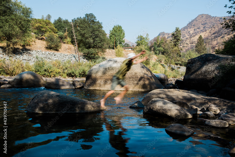 Older boy jumping across boulders at Yosemite riverbed Older boy jumping across boulders at Yosemite riverbed