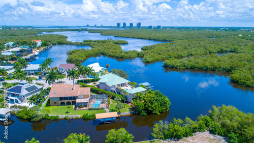 Aerial bay view with homes in Florida and high rises in the background surrounded by blue water © Ray Dukin