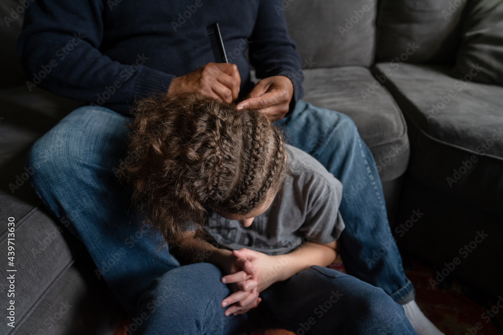 Black dad picking out braids with comb for son Black dad picking out braids with comb for son