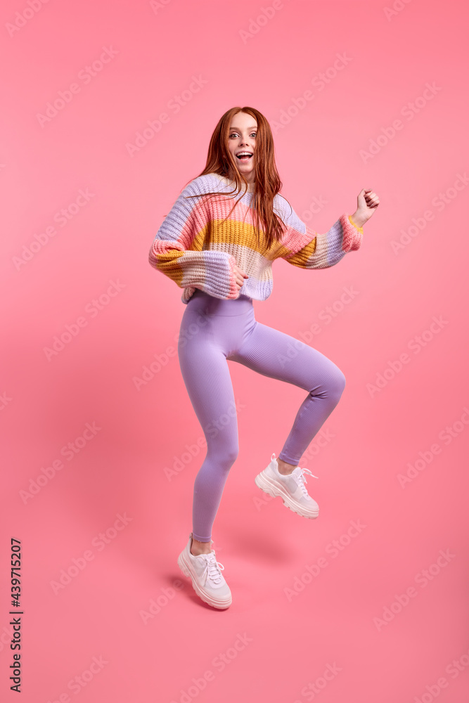 Positive lady jump high celebrate black friday sales shopping center opening, in casual sweater and leggins, isolated over pink color background. Woman in shock by discounts in shop. Copy space Positive lady jump high celebrate black friday sales shopping center opening, in casual sweater and leggins, isolated over pink color background. Woman in shock by discounts in shop. Copy space