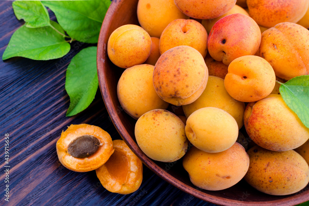 Fresh, ripe organic apricots in a bowl with leaves table Fresh, ripe organic apricots in a bowl with leaves table