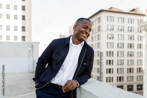 Handsome Man Smiles While Looking Over a Rooftop in the City photo