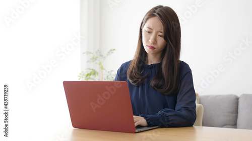 パソコンを見ながら考え事をする女性 © taka