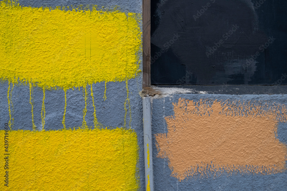 Dripping yellow and brown paint covering graffiti on building wall, close up