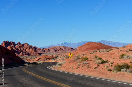 Winding scenic empty road in the desert through sandstone rocks. Blue sky.