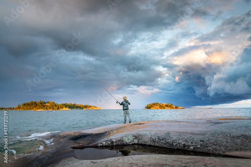 Boy Fishing with Storm Clouds on Sea Kayak Camping Trip to Georgian Bay Killarney Ontario Canada photo