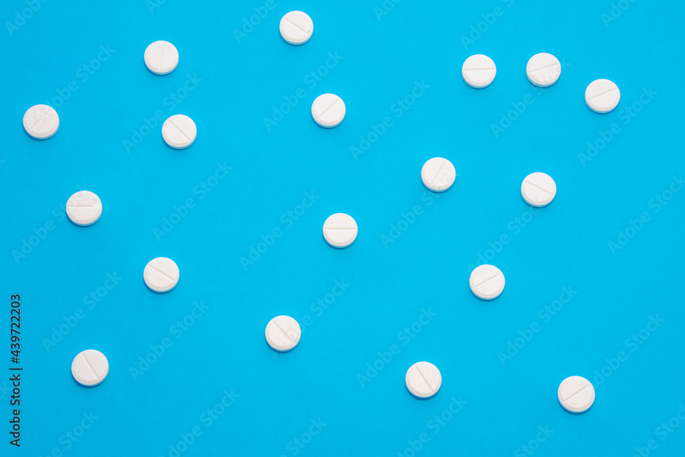Background for pharmacy or medicine. White pills with medicine are on a blue uniform background, forming a polka dot pattern
