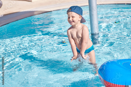 Caucasian cute toddler swims and have fun in small pool for swimming. Concept of summer vacations and fun. High quality photo. Copy space