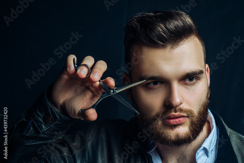 Young sexy man, portrait of guy with barber scissors for barber shop. Modern barbershop, shaving. Handsome male with modern hairstyle on black.