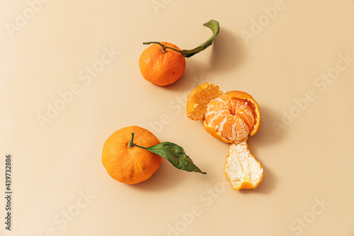 Peeled leafy oranges on orange background photo