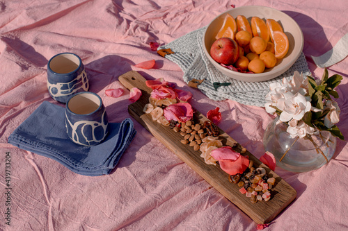 Picnic in the park with ceramic cups, lots of fruits, beautiful wooden board with nuts photo