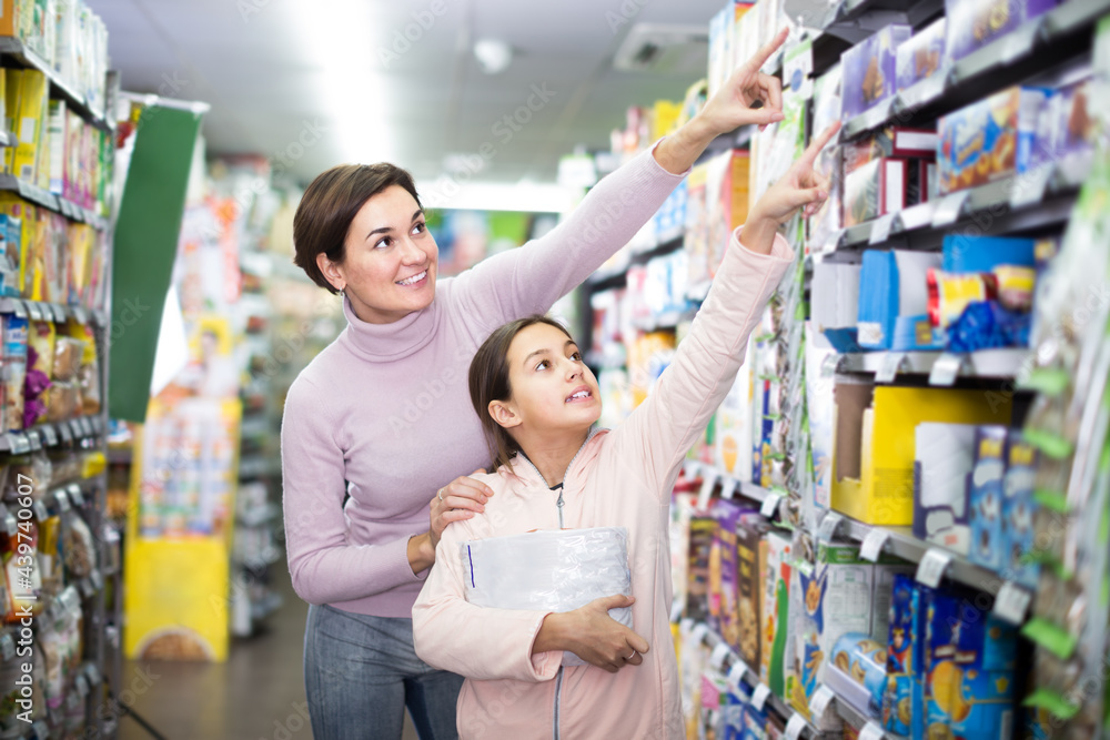 Obraz premium woman with daughter choosing delicious cookies in supermarket
