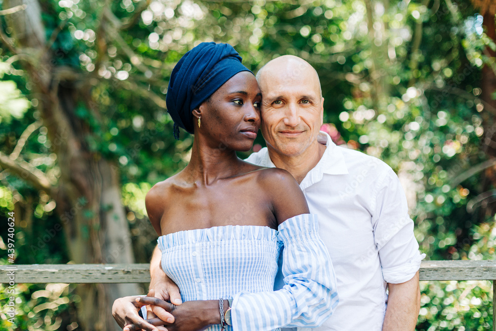 Diverse couple standing in embrace on nature Diverse couple standing in embrace on nature