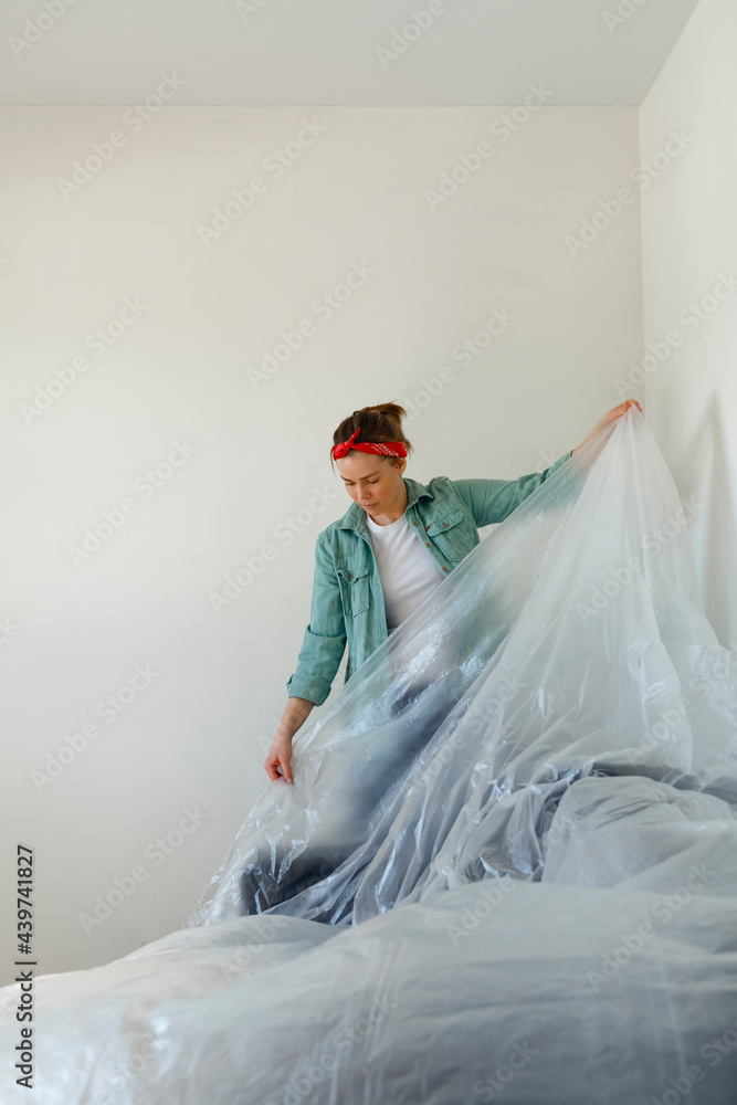 Woman covering furniture with plastic during renovation work Woman covering furniture with plastic during renovation work