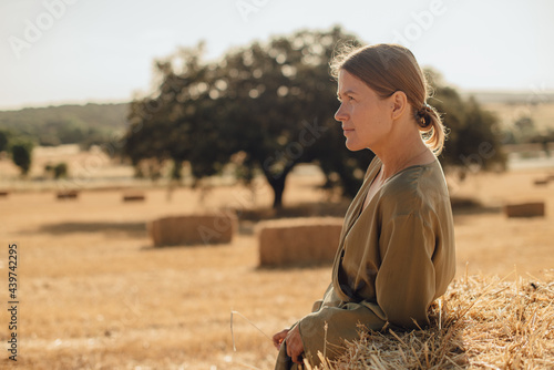 Profile of a woman leaning on hay