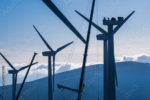 Silhouetted workers repairing a wind turbine