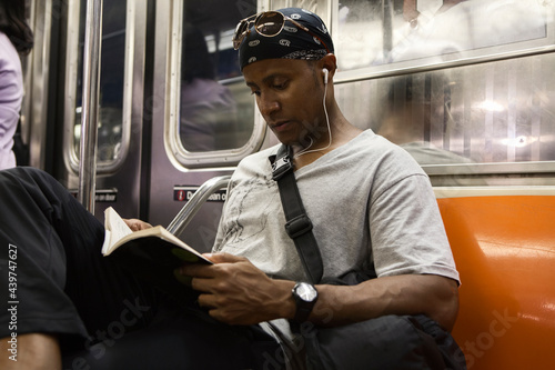 Young adult blackman riding book on the Manhattan subway  photo