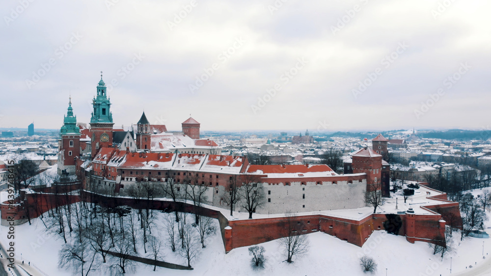Obraz premium Aerial view of the Wawel Royal castle. A castle residency located in central Krakow. A famous landmark. Panoramic view of the city skyline during the winter season. Clear white sky in the background. 