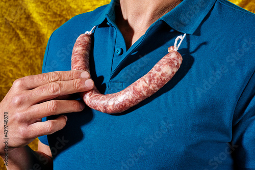 young man wears a raw pork sausage in his neck photo