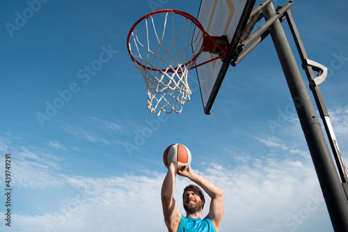 Sports men playing basketball outdoors on a sunny day.