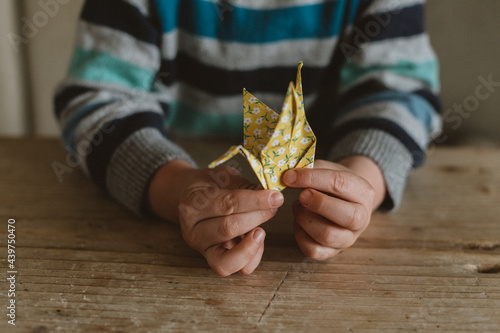 A child making origami crane with craft paper photo