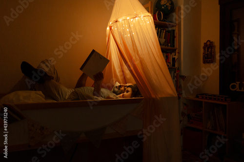 Father and daughter reading a story in bed photo