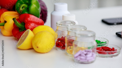 Fruits and vegetables, red, green, yellow pills in several bottles, mobile phone nutritionist table. Concept for nutritions table top view photography.