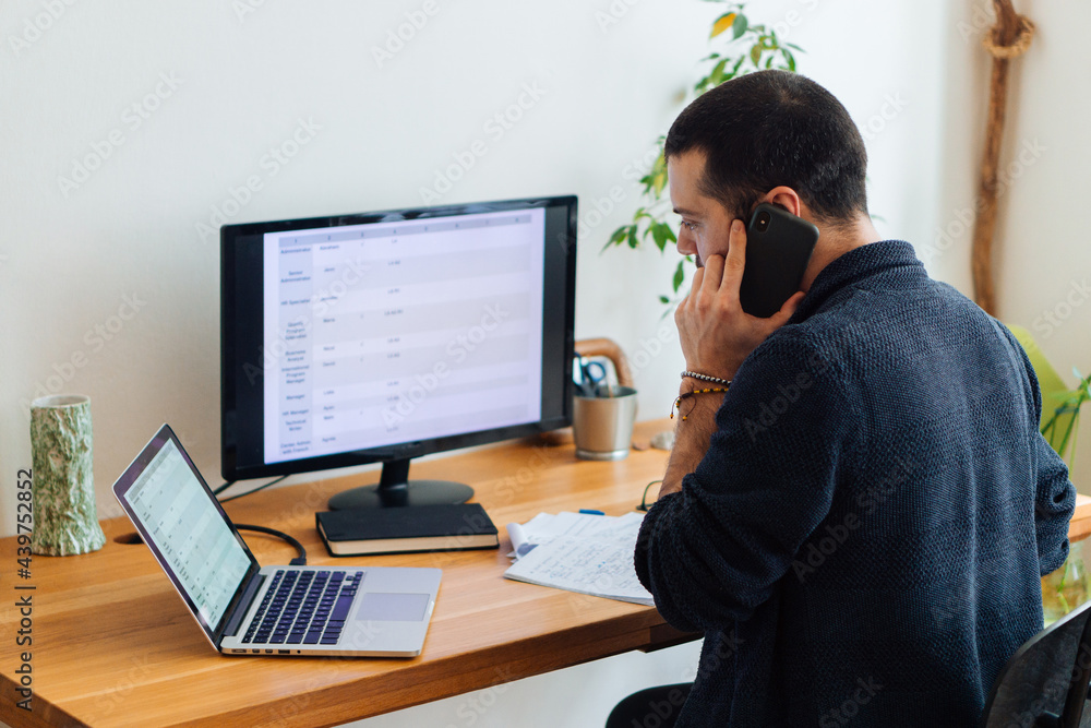 Handsome young adult man talking on the phone at home office. Handsome young adult man talking on the phone at home office.