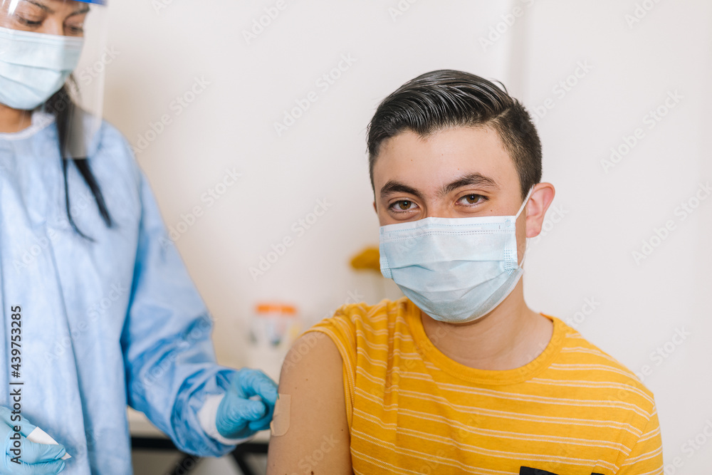 Content teenager looking at camera after COVID vaccination in clinic Content teenager looking at camera after COVID vaccination in clinic