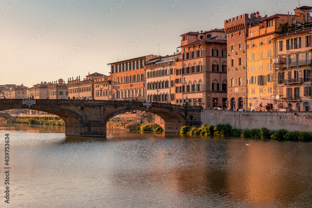 Fototapeta premium Florence, Italy -20 June, 2019 : view of St Trinity Bridge, river Arno and residential area of the city at golden hour.