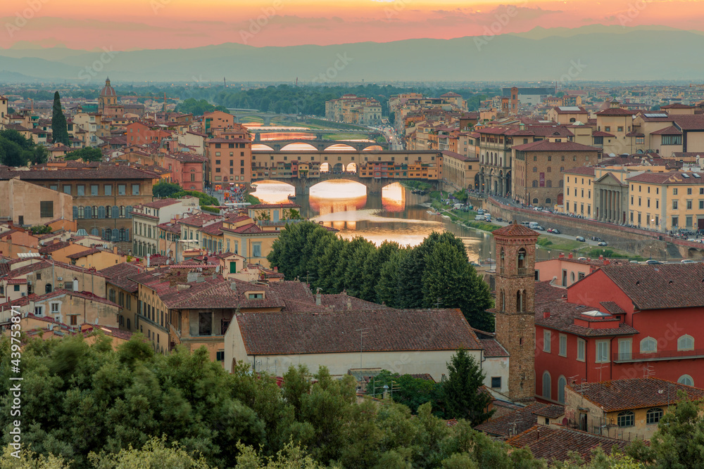 Florence, Italy - 20 June, 2019 :  panoramic overview from Arnolfo Tower (Torre di Arnolfo)at sunset haze, historical part of the city, River Arno and mountains range in sunset rays on the background 