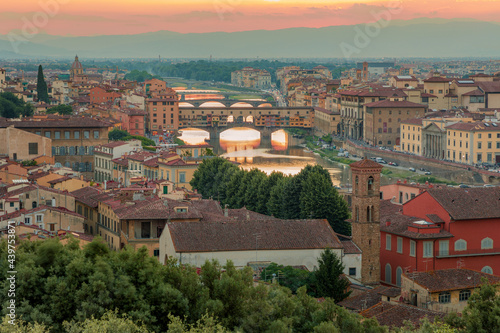 Florence, Italy - 20 June, 2019 : panoramic overview from Arnolfo Tower (Torre di Arnolfo)at sunset haze, historical part of the city, River Arno and mountains range in sunset rays on the background 