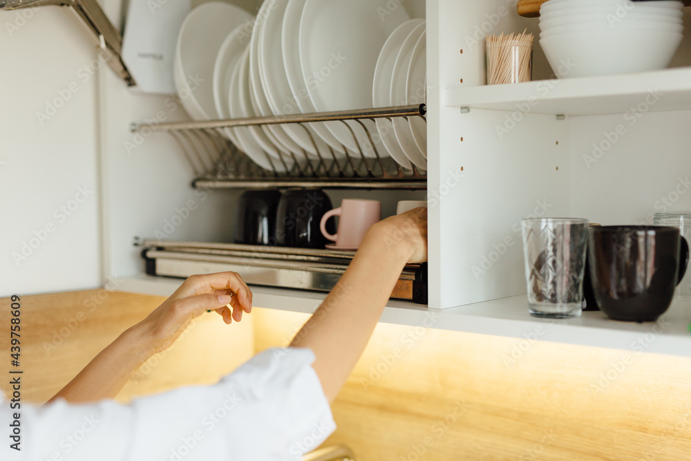 Woman Takes Dishes Off The Kitchen Shelf Woman Takes Dishes Off The Kitchen Shelf