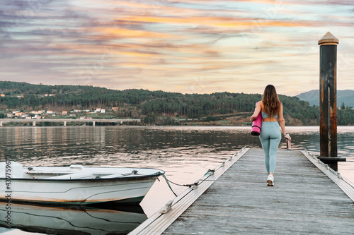 Slim sportswoman walking along wooden quay