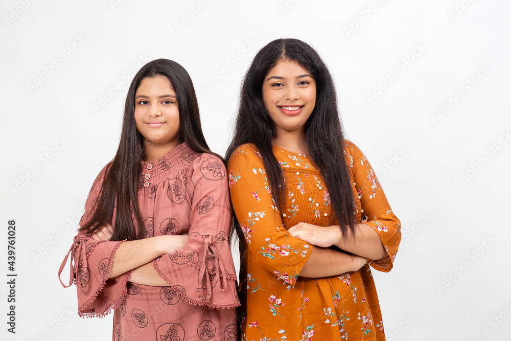 Two happy and smiling young Indian girls. Teenagers standing against white backdrop