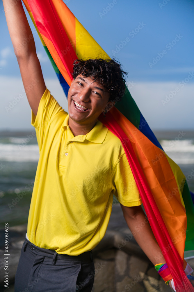 Young gay man proudly holding the lgbt flag in his hands