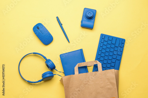 Paper bag with office accessories on a yellow background. Flat lay.