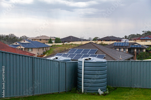 Incoming rain storm over rooftops in town and rainwater tank in backyard