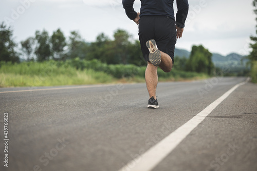 Man wearing sportswear running on the road with mountain background. Young man jogging for exercise in the nature. healthy lifestyle and sports concept.