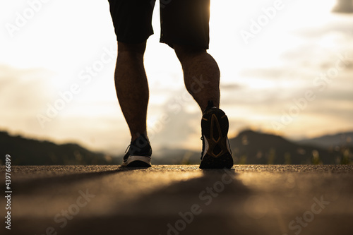 Close up running man leg on the road. Athlete jogging outdoor nature. Runner at countryside with sunrise in the morning.