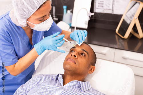 Latin american man getting injections for face skin tightening at aesthetic cosmetology clinic