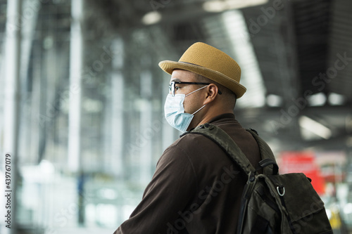 Young traveler man wearing mask to protect flu coronavirus. Walking on escalator. Tourist in airport terminal Arrival or departure passenger.Backpacker Check in to travel in downtown urban city