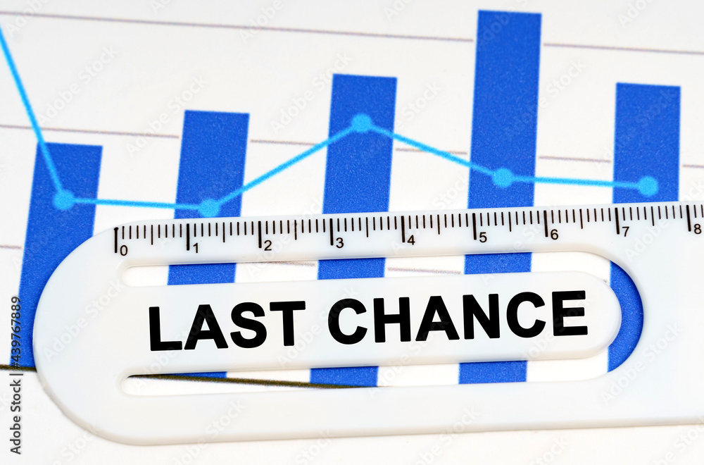 Obraz premium On the sheet with graphs there is a white ruler with the inscription - LAST CHANCE