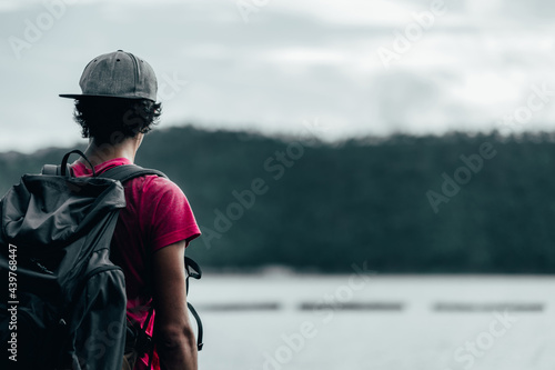 young teen Caucasian boy hipster man adult backpacker enjoying camera on beautiful landscape scenery view jungle mountains forest at Kanchanaburi water river dam National Park, Thailand.