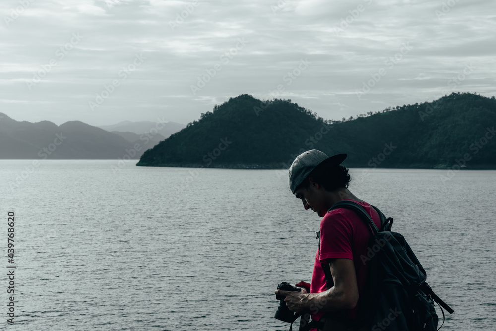 young teen Caucasian boy hipster man adult backpacker enjoying camera on beautiful landscape scenery view jungle mountains forest at Kanchanaburi water river dam National Park, Thailand. young teen Caucasian boy hipster man adult backpacker enjoying camera on beautiful landscape scenery view jungle mountains forest at Kanchanaburi water river dam National Park, Thailand.