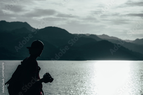 young teen Caucasian boy hipster man adult backpacker enjoying camera on beautiful landscape scenery view jungle mountains forest at Kanchanaburi water river dam National Park, Thailand.