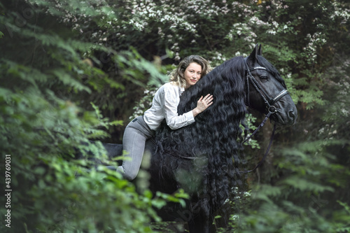 Beautiful wman riding a frisian horse in the forest. photo